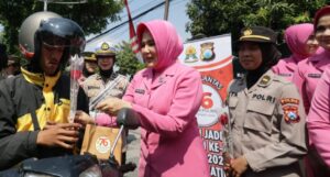 Sapa Warga di Hari Jadi ke -76, Polwan Polrestabes Surabaya Turun Jalan Berbagi Helm dan Bunga